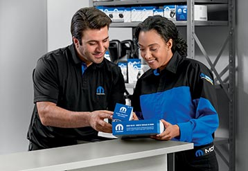 Two employees look at Mopar® aftermarket parts.