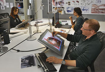 Employees seated around a large table working on computers.