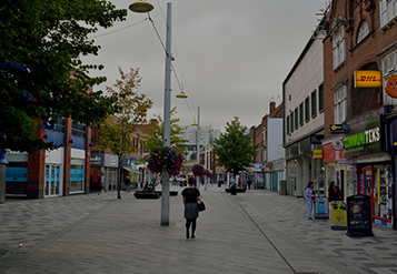 Neighborhood street lined with shops and trees.