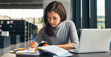 도서관에서 책과 노트북을 가지고 있는 여학생
