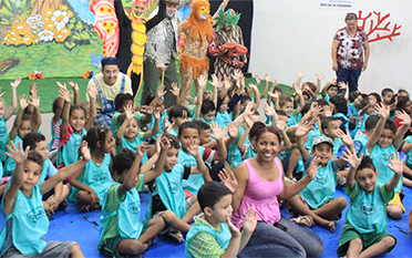 LATAM-whychoose-arvore-ko 터키석 파란색 티셔츠를 입고 손을 들고 흔드는 많은 어린이들